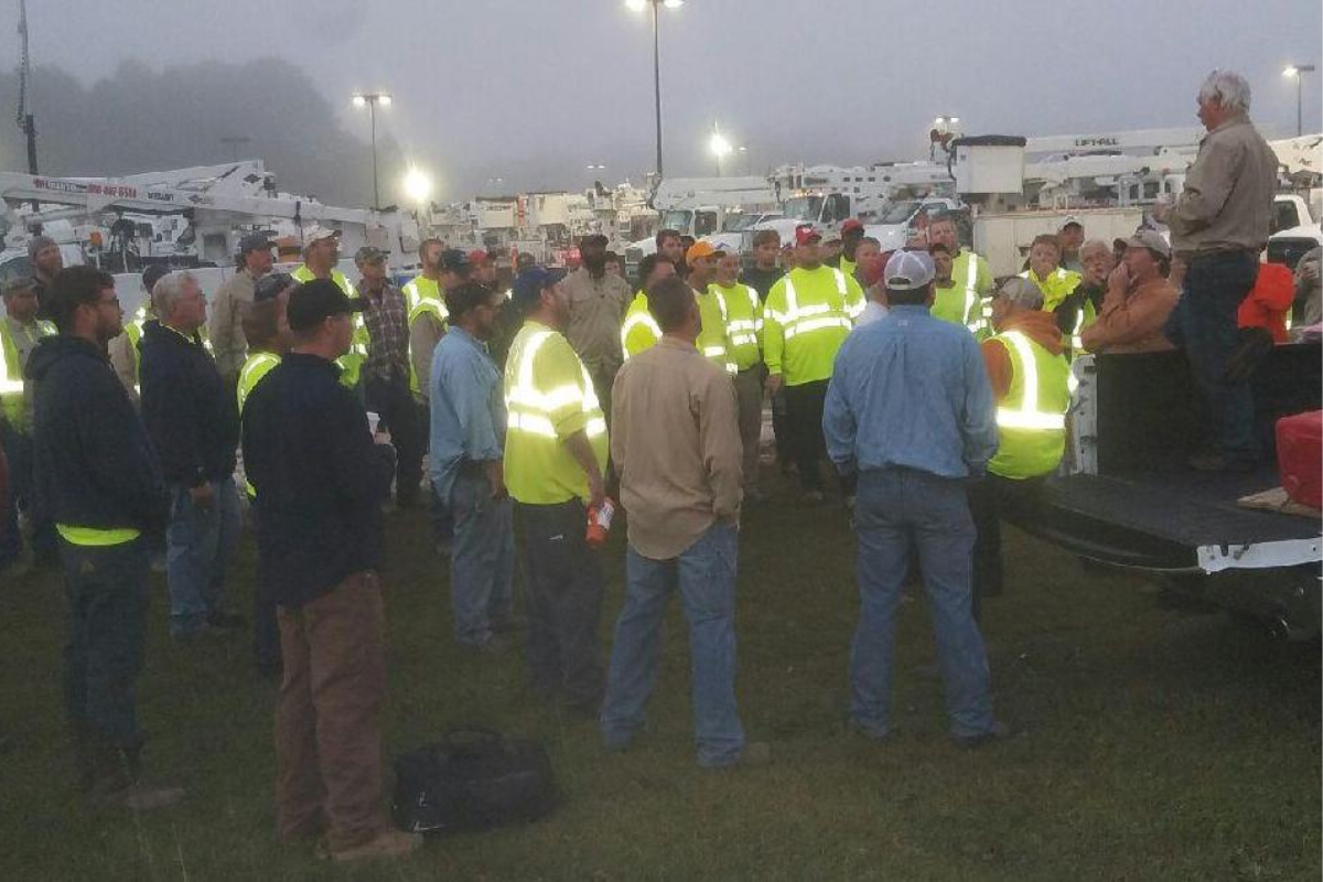 A large group of field workers gather around for a speech.